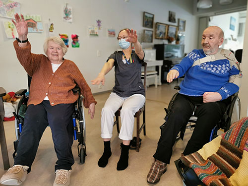 Ett par äldre och en sjuksköterska dansar på äldreomsorgen.