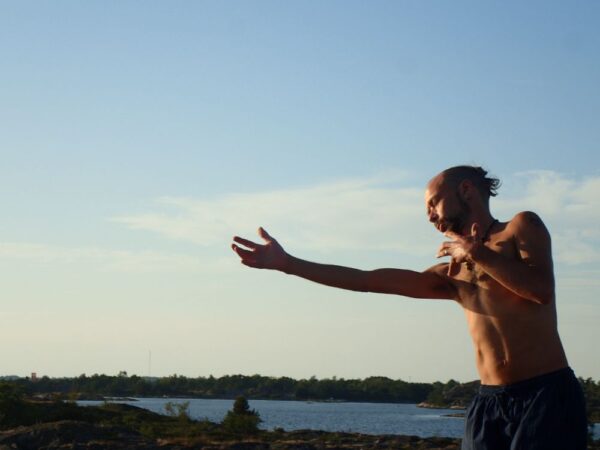 Gabriel dansar framför havet utan t-shirt.