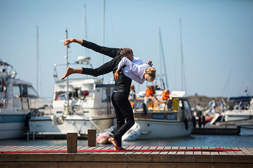 Gabriel and Elinmaria performing on a pier in front of the boats