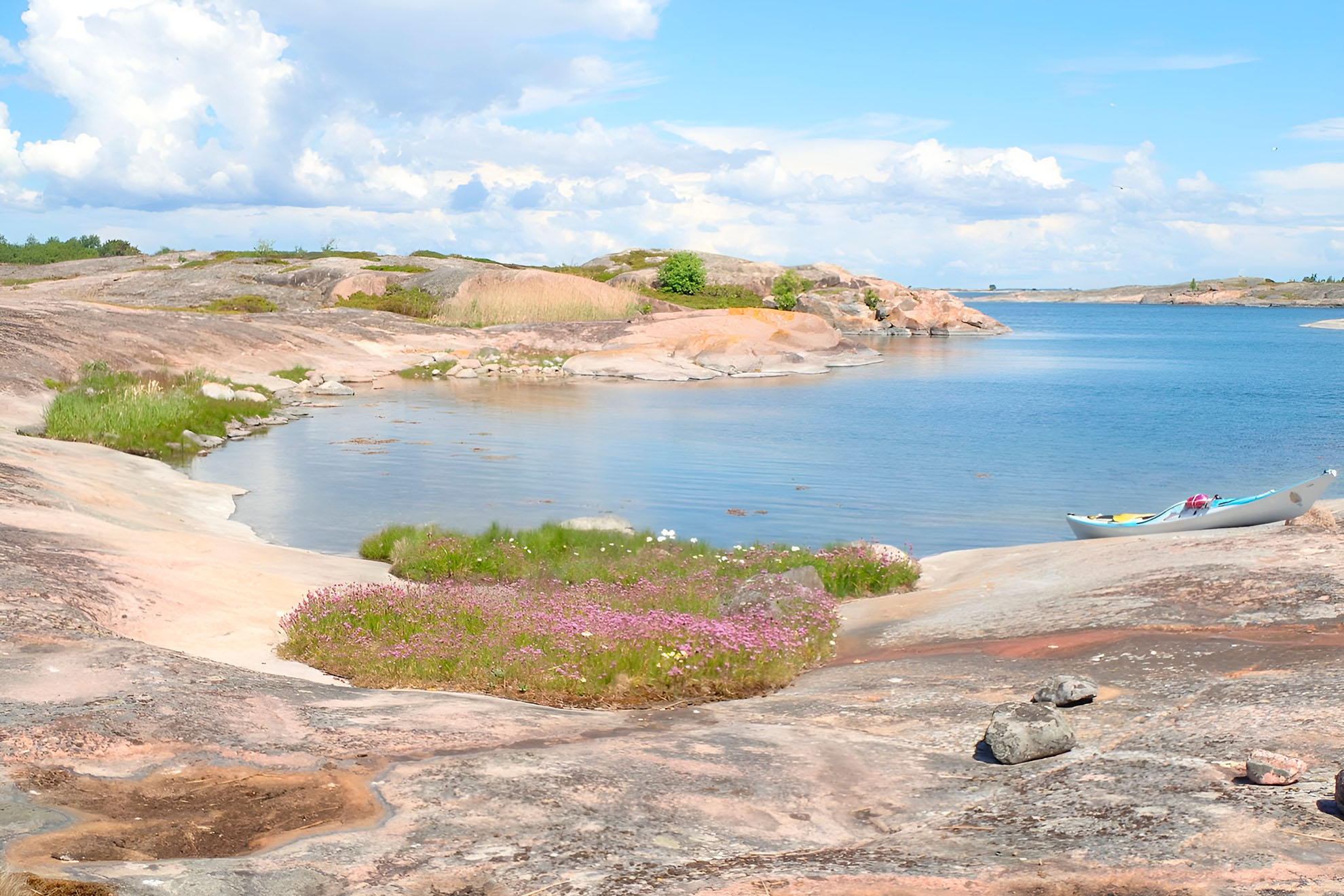 Ett vackert pastellfärgat havslandskap med en kajak på stranden.
