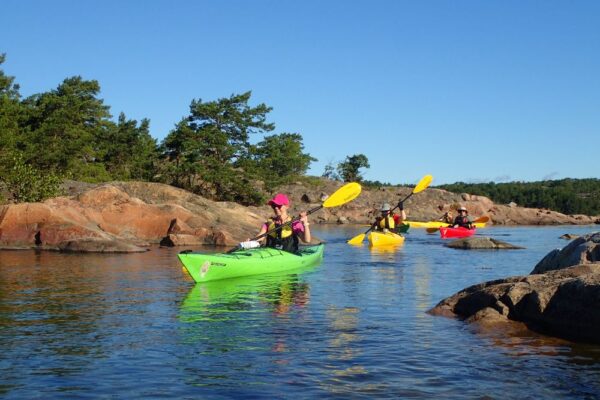 A group of three people kayaking in the archipelago sea