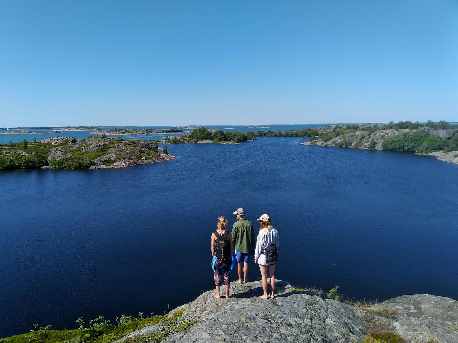 Three people admiring the archipelago sea from a cliff