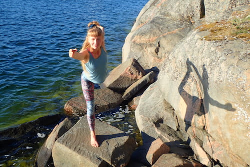 ElinMaria övar yoga på en klippa medan hon tittar på kameran.