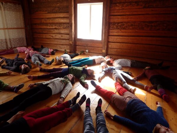 A group of people lying down and relaxing in a spacious room inside an old wooden house.