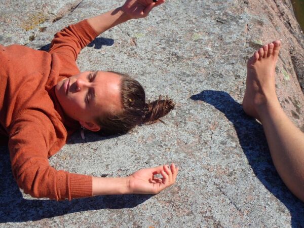 The torso of a girl and the foot of another person in laying in the rocks