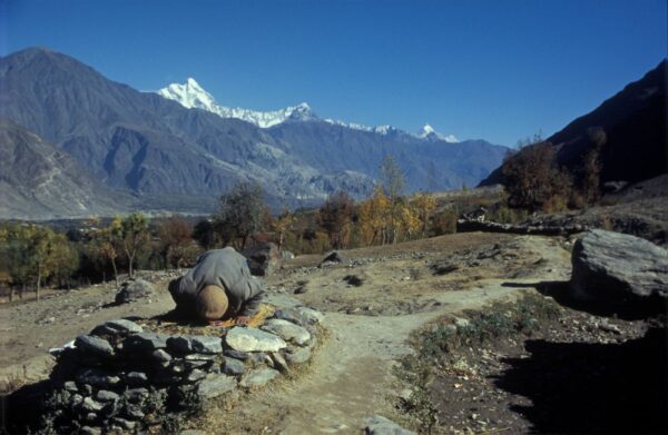A person praying with huge mountains in the background