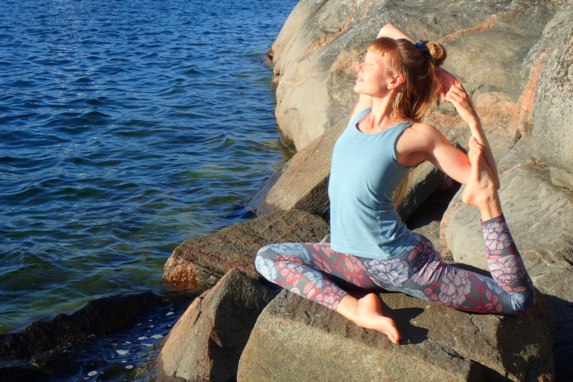 Elin Maria in a yoga pose on the rocks in front of the sea
