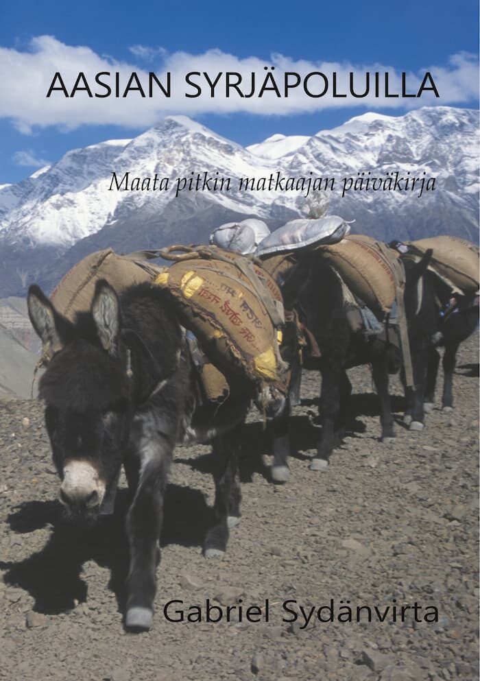 A caravan of donkeys carrying loads walks along a rocky path with snow-capped mountains in the background. The text reads "Aasian Syrjäpoluilla" by Gabriel Sydänvirta.